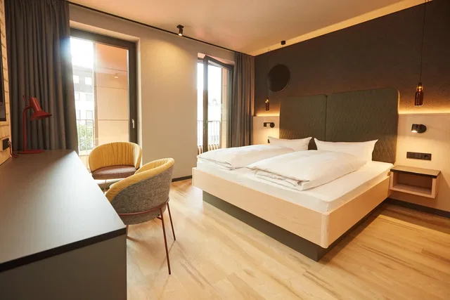 Doppelzimmer im Hotel Zum Goldenen Hirsch mit Balkon und zwei Sesseln.