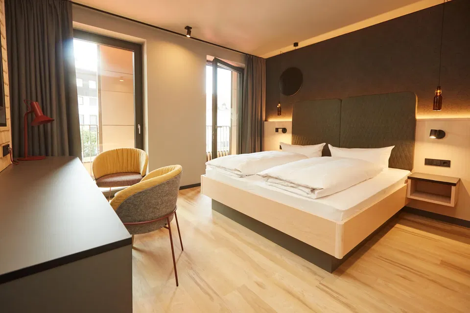 Doppelzimmer im Hotel Zum Goldenen Hirsch mit Balkon und zwei Sesseln.