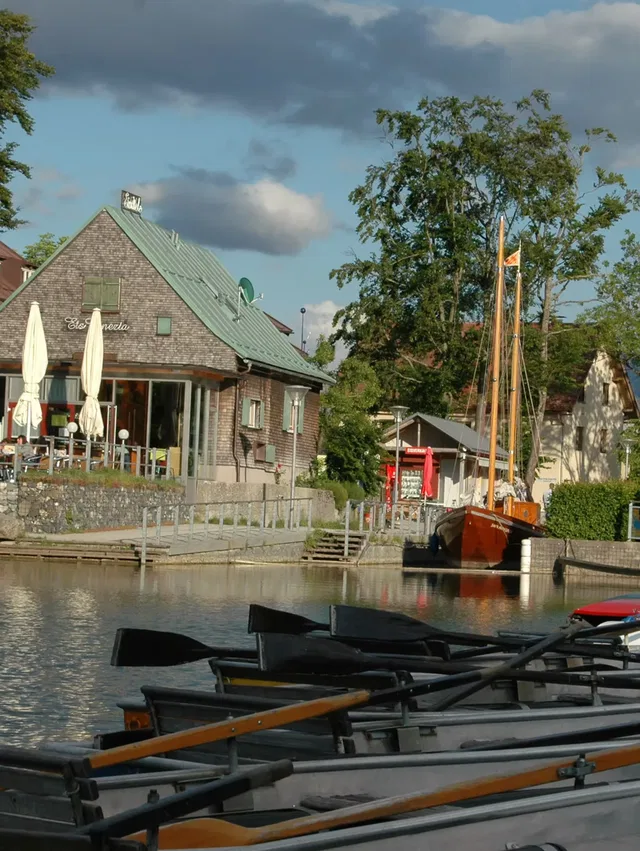 Hafen mit Booten am Ufer, Cafégebäude und Segelboot am Kai