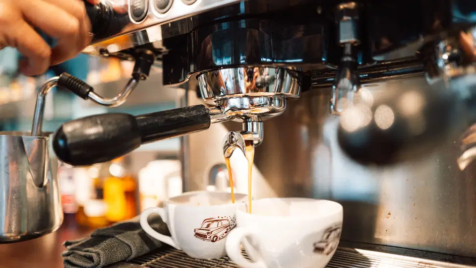Espressomaschine gießt Kaffee in zwei Tassen