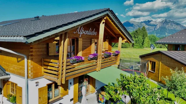 Holz-Chalet Alpenliebe mit Balkonblumen und Bergblick