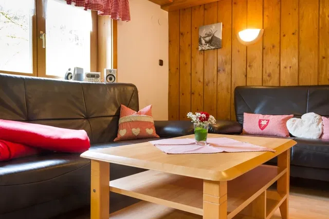Gemütliches Wohnzimmer mit Holzwänden, Ledersofas und Holz-Couchtisch