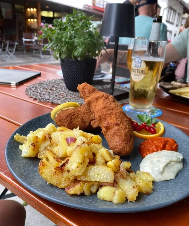 Paniertes Gericht mit Bratkartoffeln und Dips auf der Terrasse des Malina