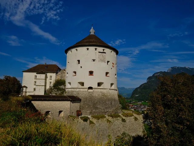 Runder weißer Wehrturm einer Burg vor Berglandschaft