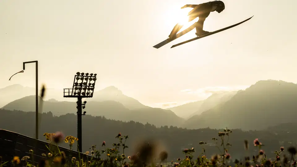Skispringer springt spektakulär über eine Schanze bei Sonnenuntergang