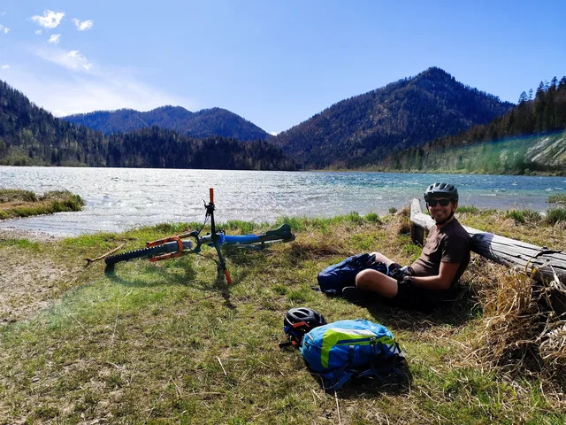 Mann mit Fahrrad am Ufer eines Bergsees