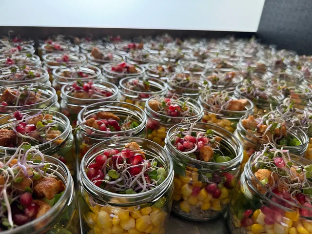 Kleine Gläser mit buntem Snacksalat aus Mais, Granatapfelkernen, Sprossen und Croutons