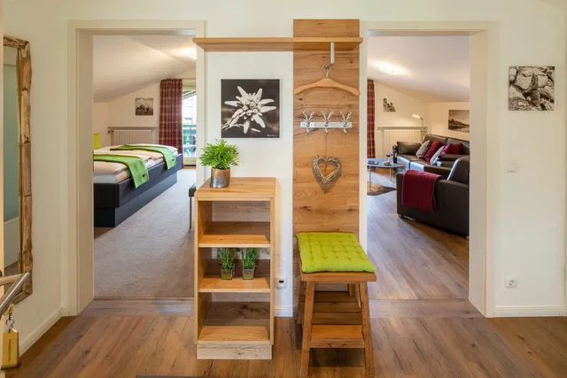 Flur mit Holzregal, Hakenleiste und gepolsterter Bank; Zimmer mit Schlafzimmern und Wohnzimmer dahin