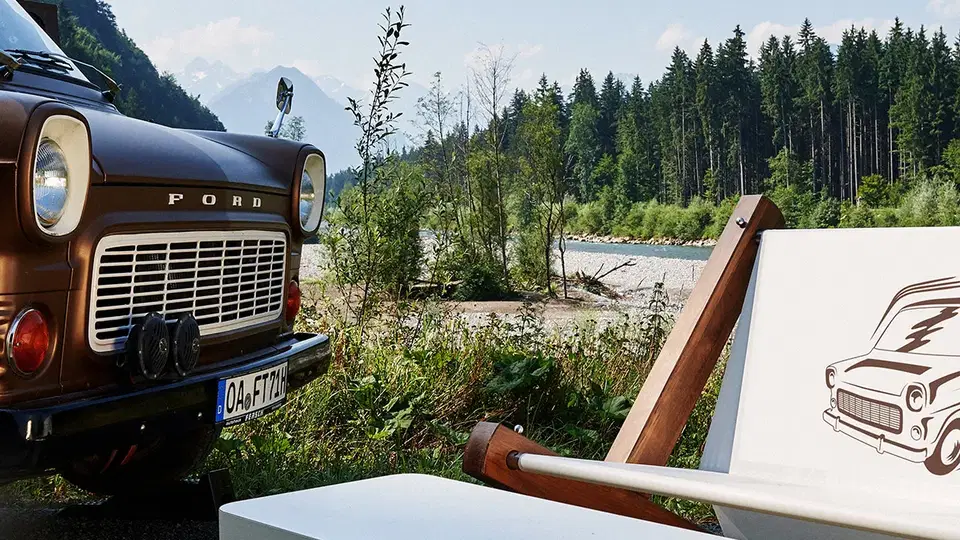 Vintage Ford Truck neben weißer Sitzbank am Flussufer, Wald im Hintergrund