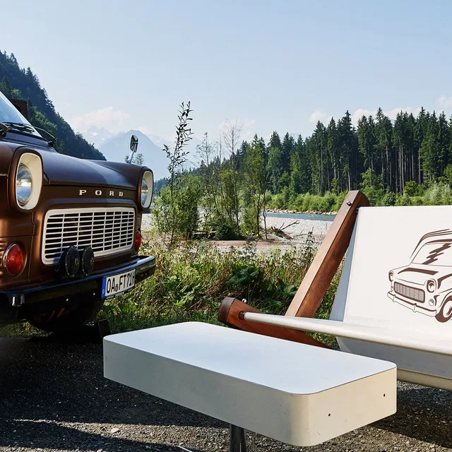 Vintage Ford Truck neben weißer Sitzbank am Flussufer, Wald im Hintergrund
