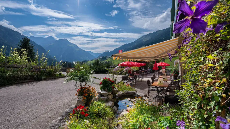 Sonnenterrasse des Gasthof Alpenblick mit roten Schirmen und Bergpanorama