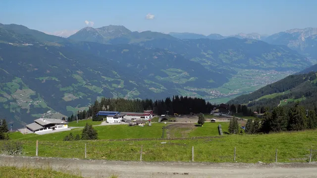 Panoramablick über ein alpines Tal mit Bergstation im Vordergrund