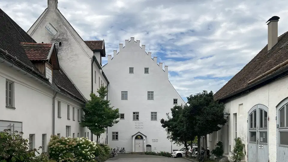 Weißes Gebäude mit Treppengiebel in einer ruhigen Straßenszene.