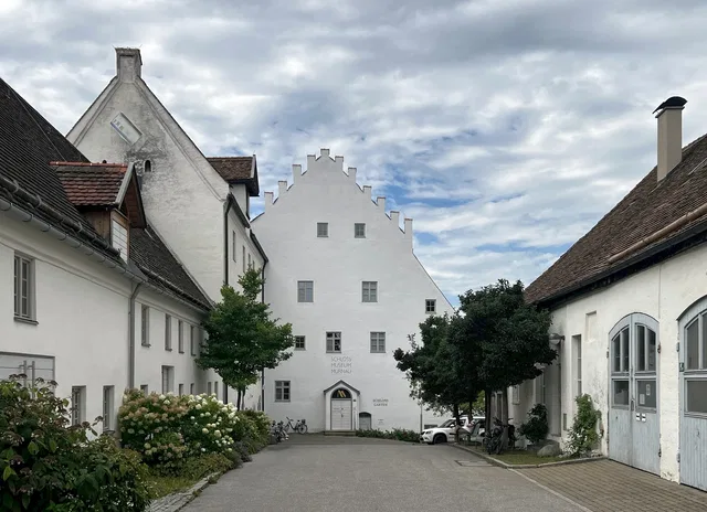 Weißes Gebäude mit Treppengiebel in einer ruhigen Straßenszene.