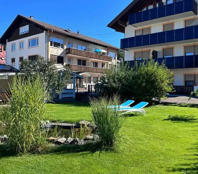 Hotel Garni Schmideler mit Garten und blauen Liegestühlen