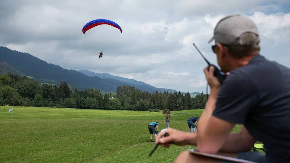 Fluglehrer begleitet einen Gleitschirmflug per Funk am Wiesenlandeplatz.
