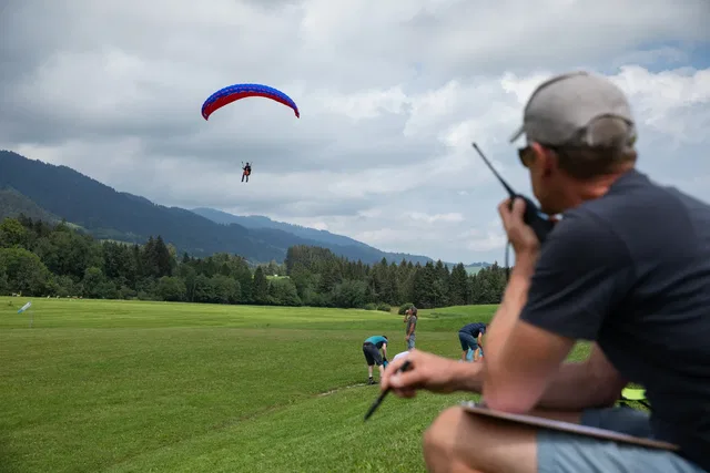 Fluglehrer begleitet einen Gleitschirmflug per Funk am Wiesenlandeplatz.