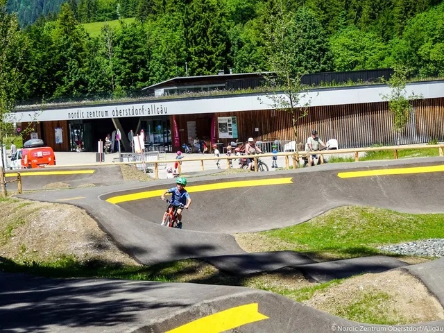 Radfahrer auf dem Pumptrack vor dem Besucherzentrum mit Zuschauern