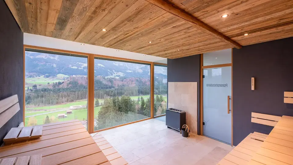 Panoramasauna mit Holzbänken und Bergblick