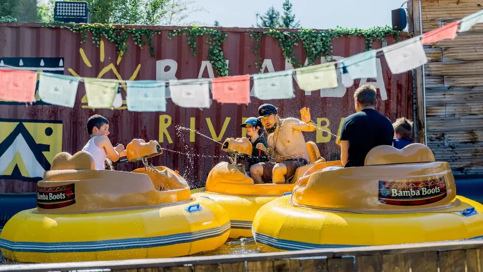 Familie fährt mit gelben Bamba-Booten und nutzt die Wasserkanonen im Wasser.