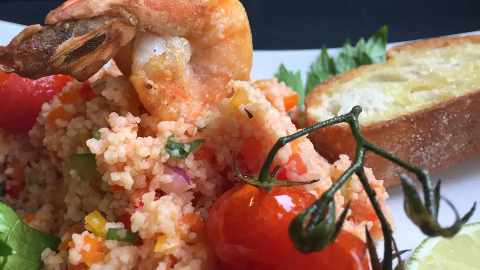 Couscous mit Garnelen, gegrillter Tomate am Zweig, Knoblauchbrot und Limette