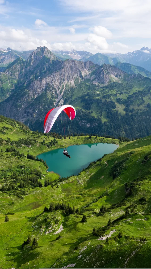 Paraglider über alpinem Bergsee vor Bergkulisse.