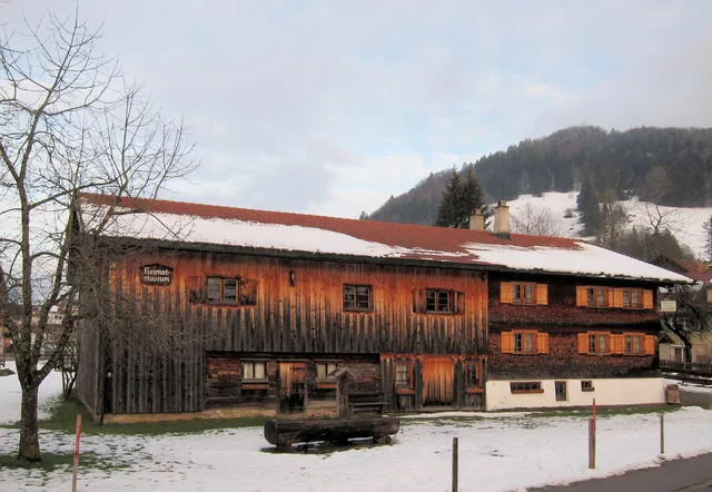 Rustikale Holzhütte mit Schneedecke vor Bergen