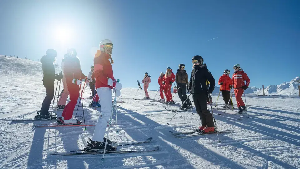 Skischulgruppe auf der sonnigen Skipiste
