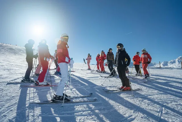 Skischulgruppe auf der sonnigen Skipiste