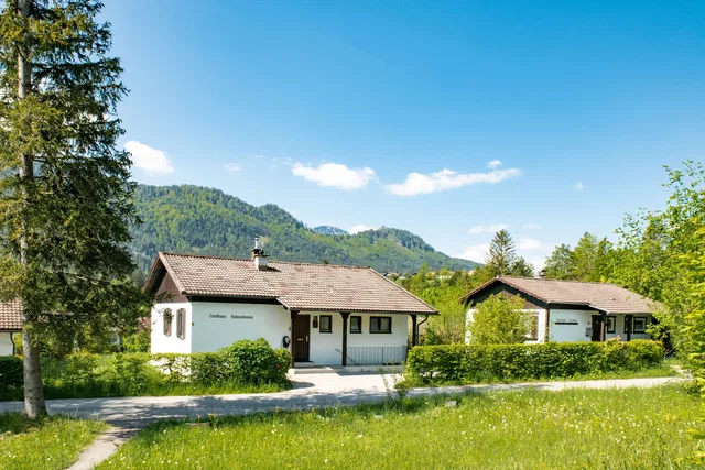 Ferienhäuser im Feriendorf Weissensee mit Wiese und Bergen im Hintergrund