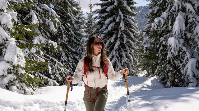 Frau mit Trekkingstöcken im verschneiten Wald