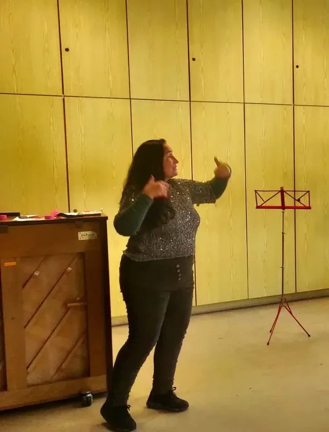 Sängerin beim Gesangsworkshop Nonnenhorn vor Holzpaneelwand, Klavier links, Notenständer rechts.