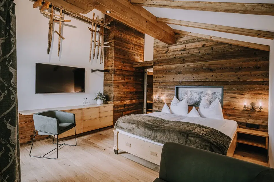 Doppelbett, Fernseher und sichtbare Holzbalken in der Suite Gaisberg.