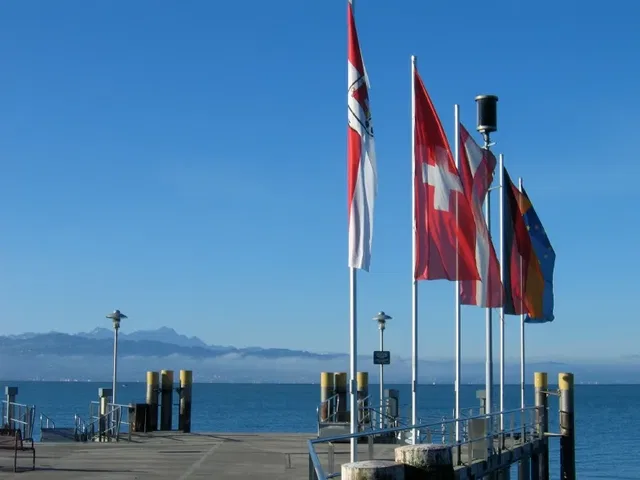 Flaggen am Pier am See mit Schweizer Flagge, Berge im Hintergrund.