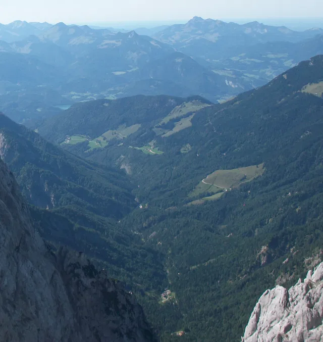 Berglandschaft mit Tälern, Wald und felsigem Vordergrund.
