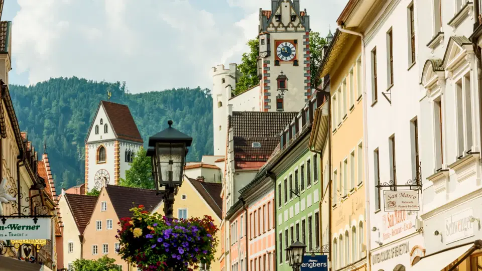 Historische Altstadtstraße mit Uhrturm, Kirche und bewaldeten Hügeln