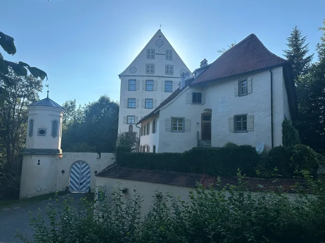 Historisches weißes Schloss mit Giebeldach, kleinem Turm und Gartenumgebung