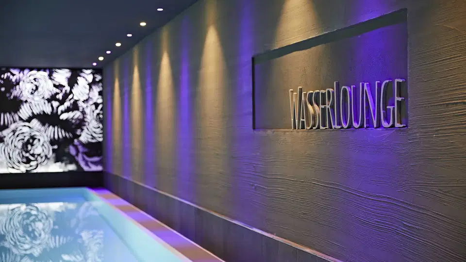 Innenpool der WasserLounge mit beleuchteter Wand im Hotel Rosenstock