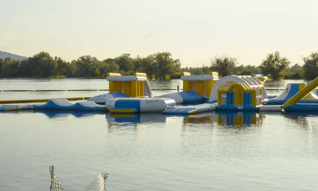 Schwimmender Wasserparcours mit Gelb-Blau-Inflatables auf einem ruhigen See
