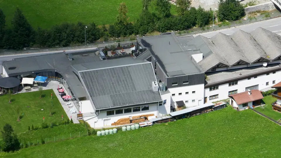 Quellalpin in Feichten mit Dachflächen, Wiese und angrenzender Straße