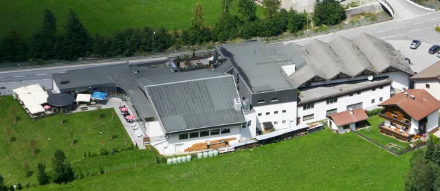 Quellalpin in Feichten mit Dachflächen, Wiese und angrenzender Straße