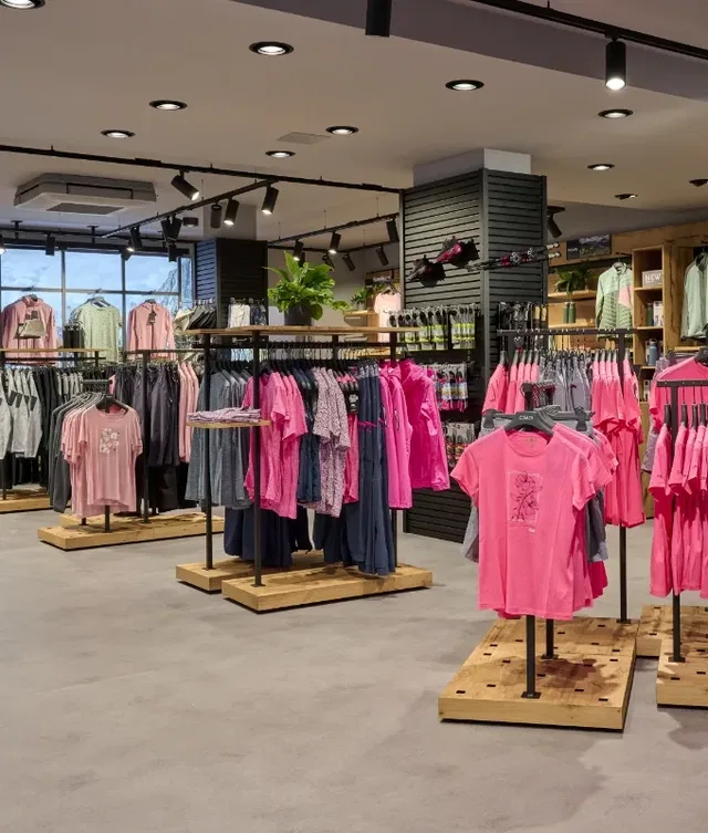 Pinkfarbene T-Shirts hängen an Stangen in einem modernen Boutique-Laden