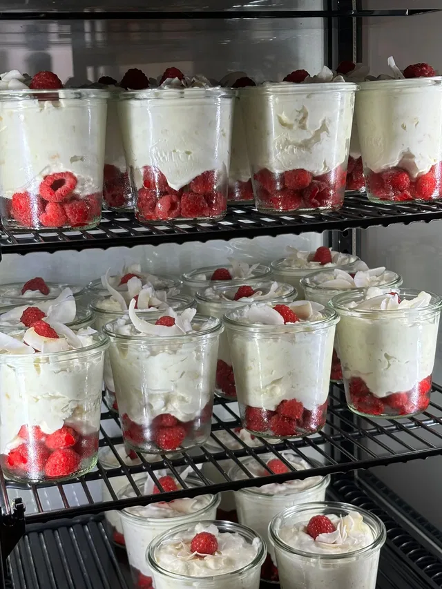Dessertgläser mit Sahne und Himbeeren im Kühlregal.
