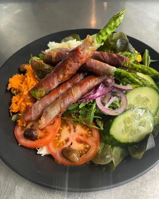 Salatplatte mit Spargel im Baconmantel, Tomaten, Gurken, Oliven und Rotkohl