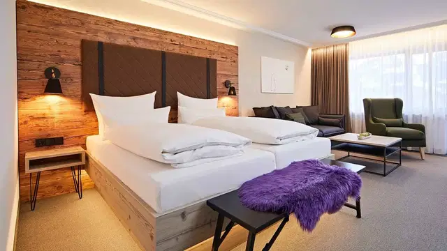 Hotelzimmer mit Doppelbett, Holz Kopfteil, Sofa-Ecke und Fensterausblick