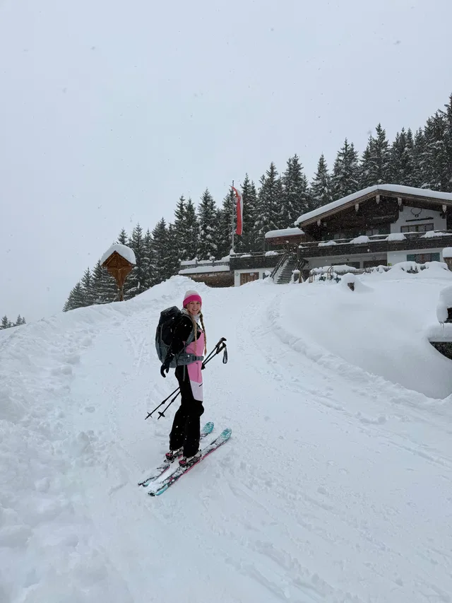 Skifahrerin mit Rucksack vor Berghütte im Schnee