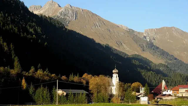 Kirche und Wiesen in Bach vor der Bergkulisse.