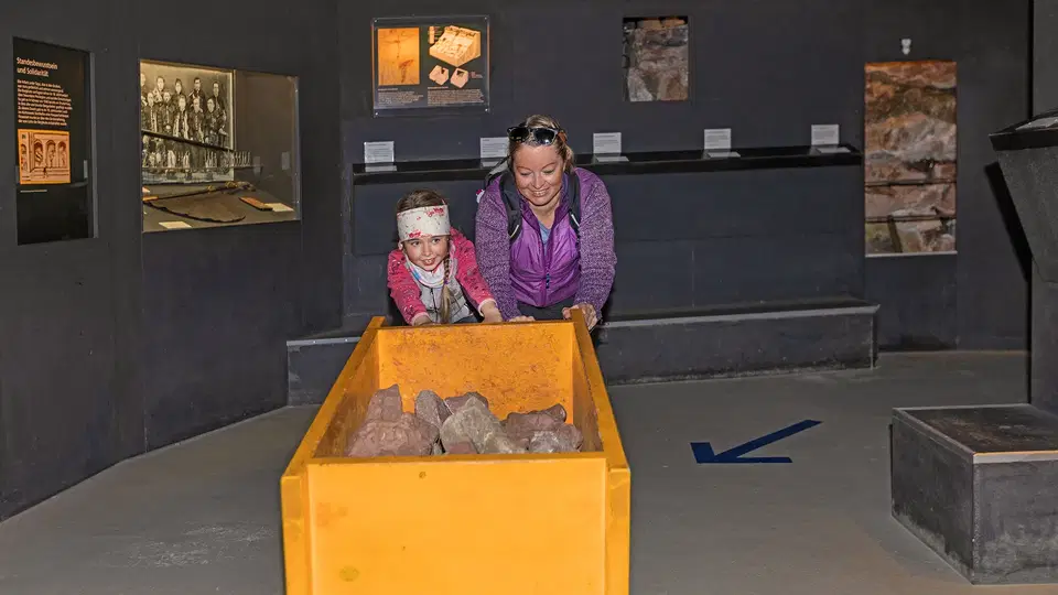 Erwachsene und Kind mit einem Grubenhunt in der Bergbau-Ausstellung