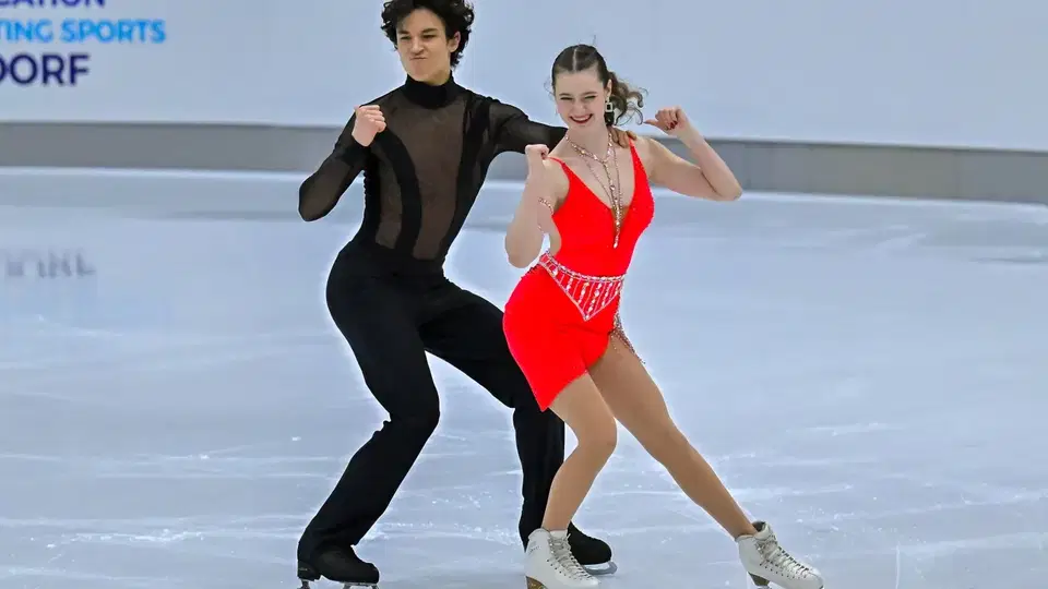 Eiskunstlaufpaar mit rotem Kleid und schwarzer Kleidung