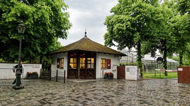 Eingang des Botanischen Gartens Augsburg mit Kassenhäuschen und Gewächshäusern